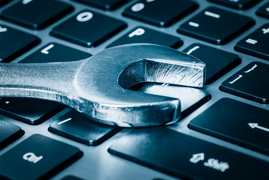 Computer maintenance - Metallic wrench over a computer keyboard toned in blue